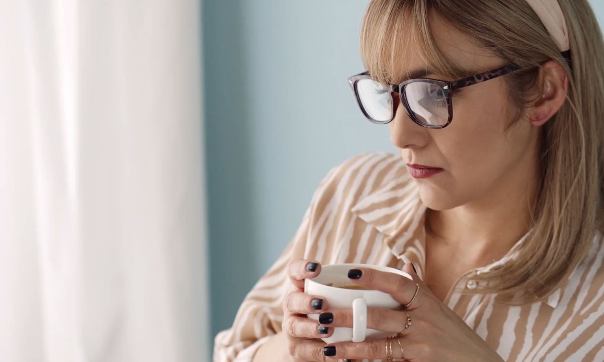 ženska osoba pije napitak iz šolje i sedi na ugaonoj