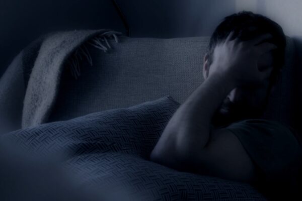 Muškarac se drži za glavu u krevetu, dok ima problem sa spavanjem