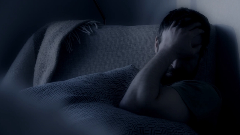 Muškarac se drži za glavu u krevetu, dok ima problem sa spavanjem