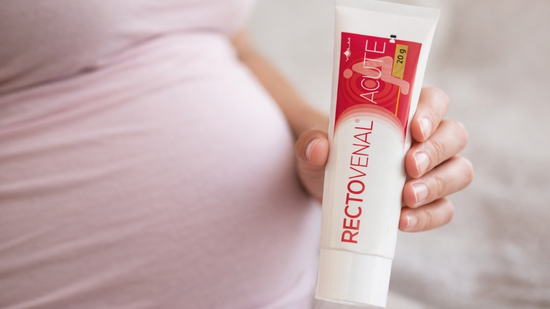 Trudnica drži pakovanje anorektalnog gela Rektovenal Acute u ruci, kao primer preparata namenjenog lokalnoj primeni kod hemoroida u trudnoći i osetljive kože