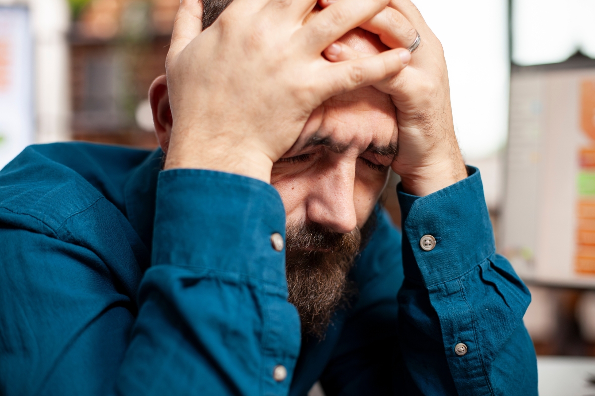 muškarac srednjih godina se drži za glavu