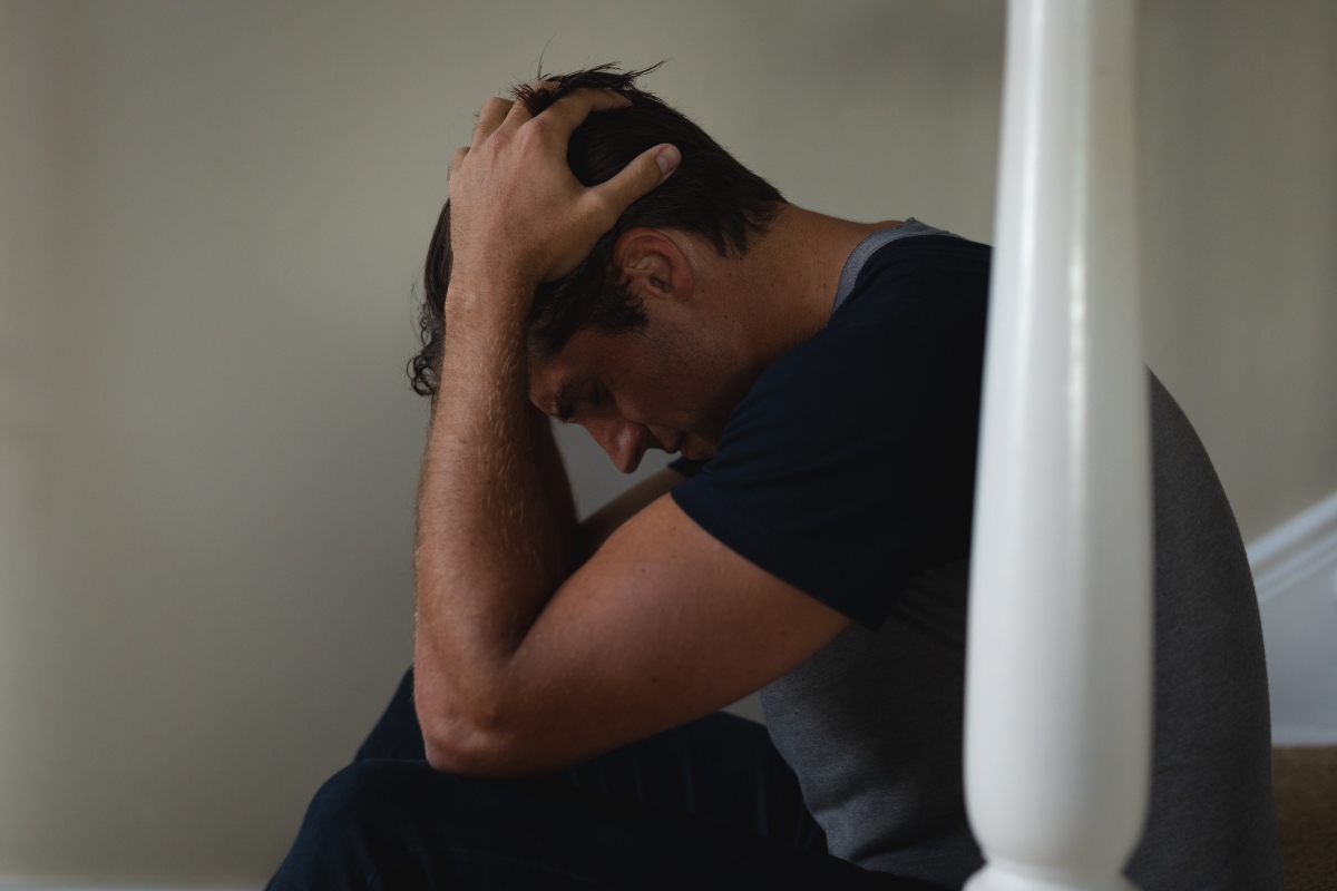 momak sedi na stepenicama i drži se za glavu