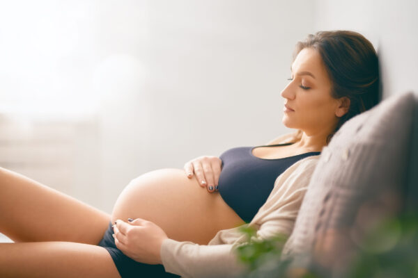 Buduća mama tokom trudnoće odmara i drži ruke na stomaku