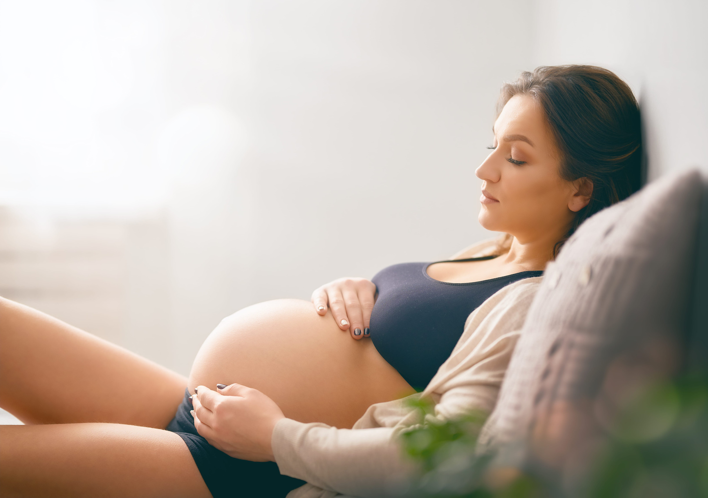Buduća mama tokom trudnoće odmara i drži ruke na stomaku
